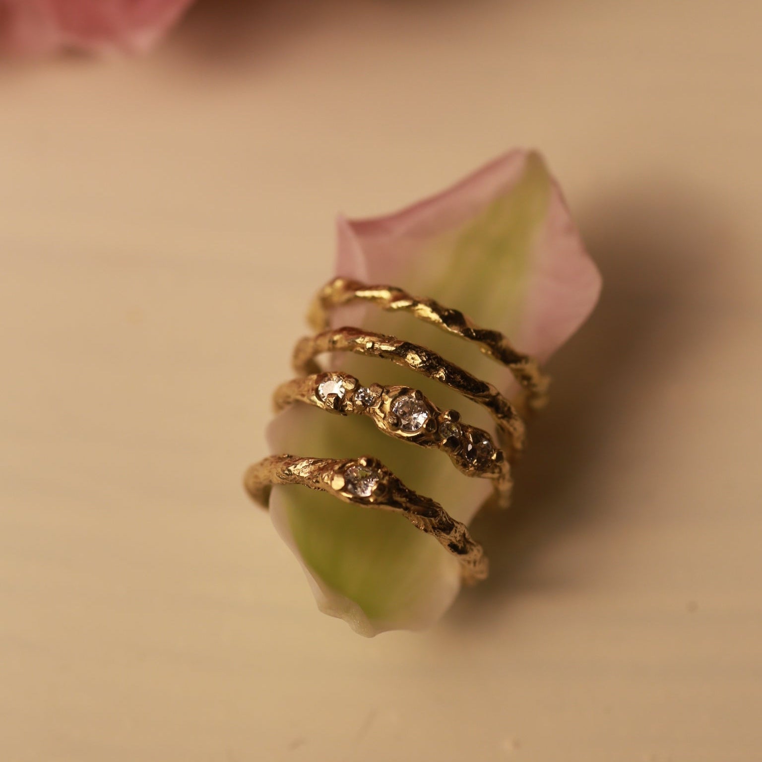 Gold ring with black accents on a pink flower with a blurred background