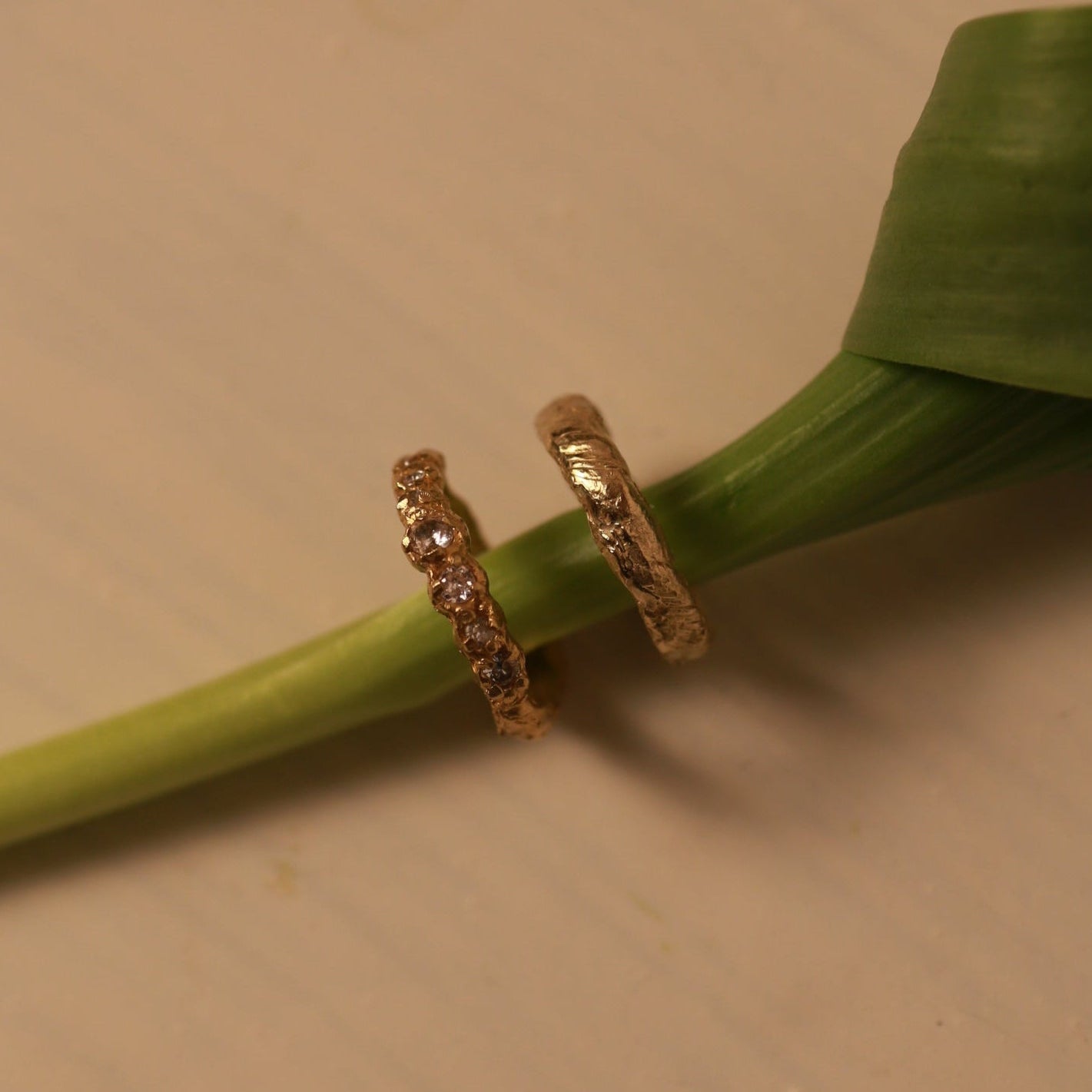 Gold ring on a green leaf against a beige background