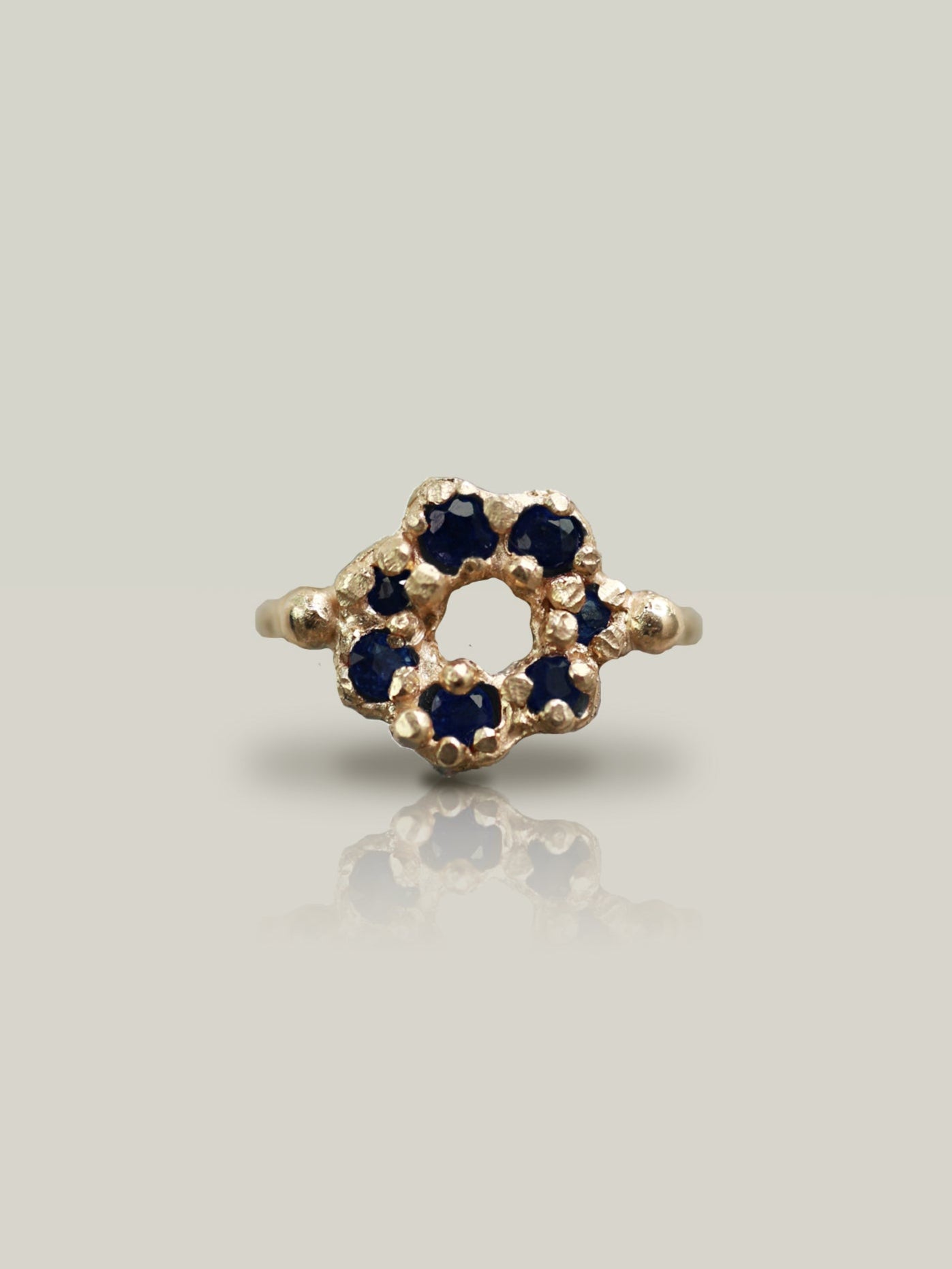 Gold ring with blue gemstones on a light gray background