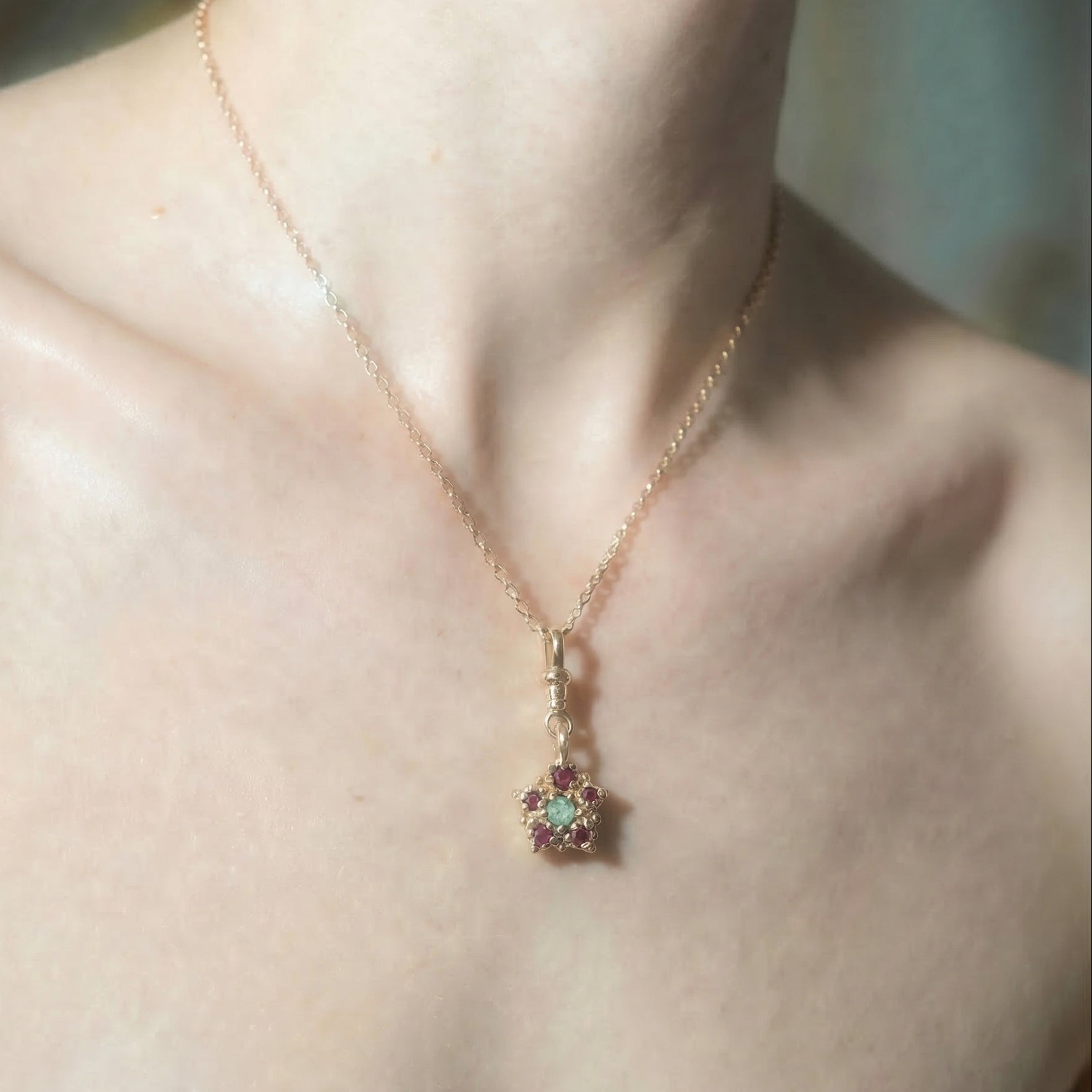 9ct yellow gold victorian inspired charm necklace set with a central emerald and surrounding rubies, on model
