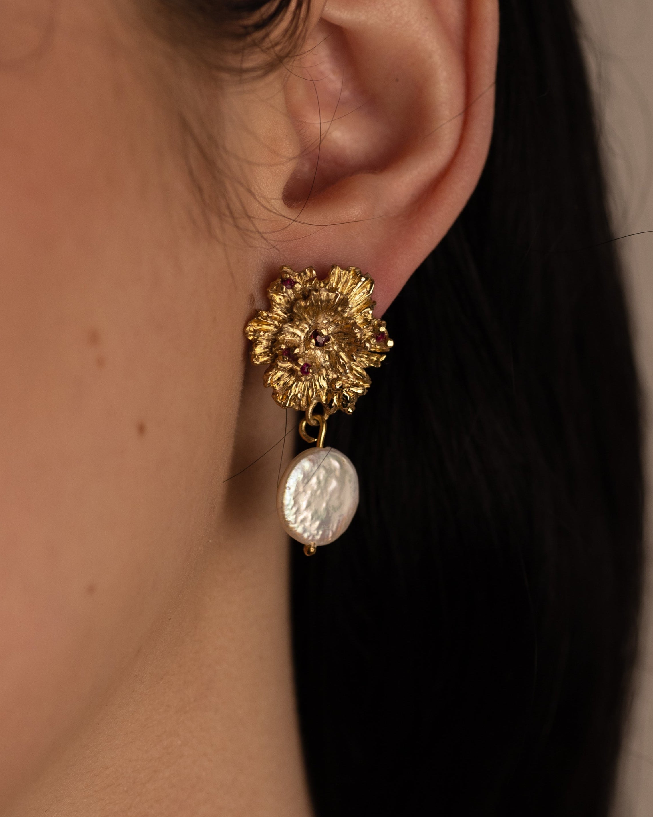 Close-up of a person wearing a gold and pearl earring.