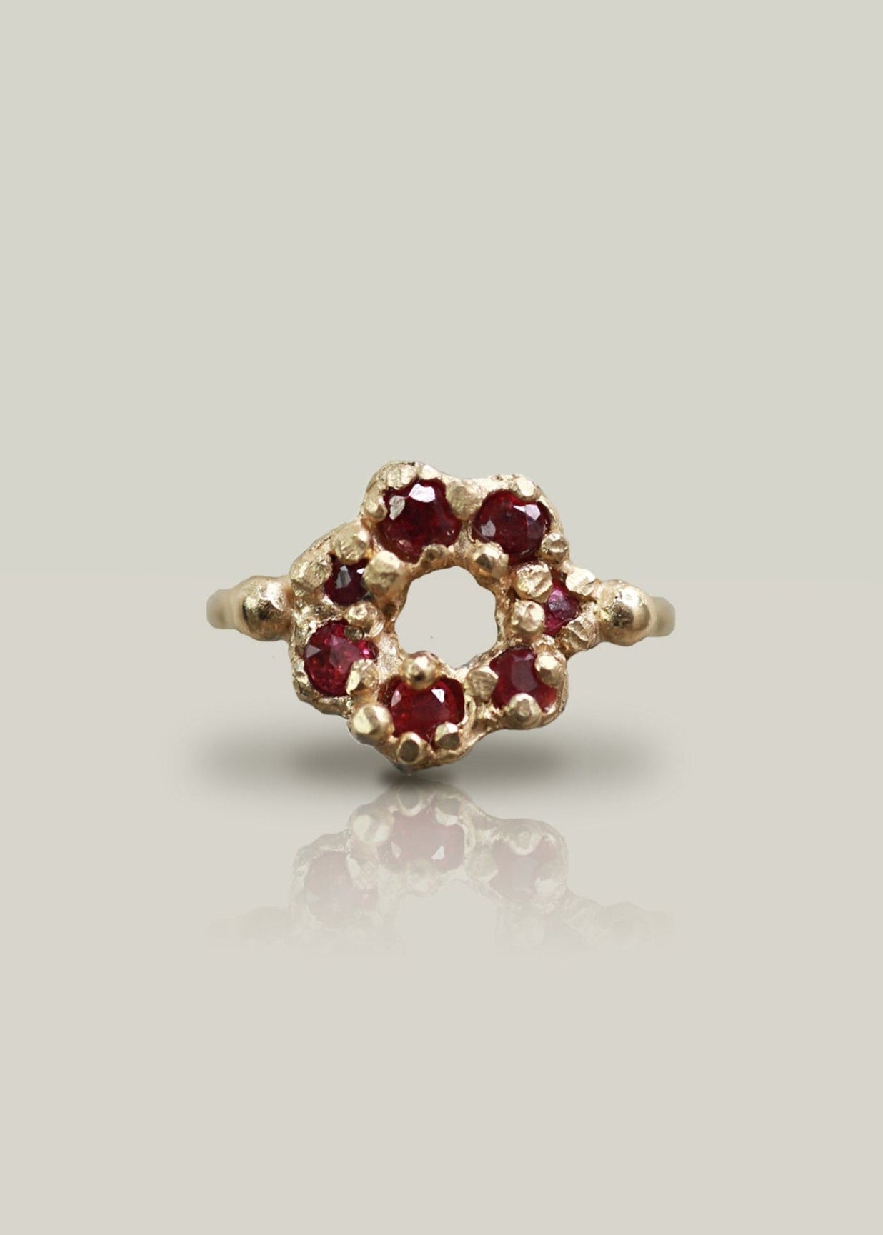 Gold ring with red gemstones on a light gray background