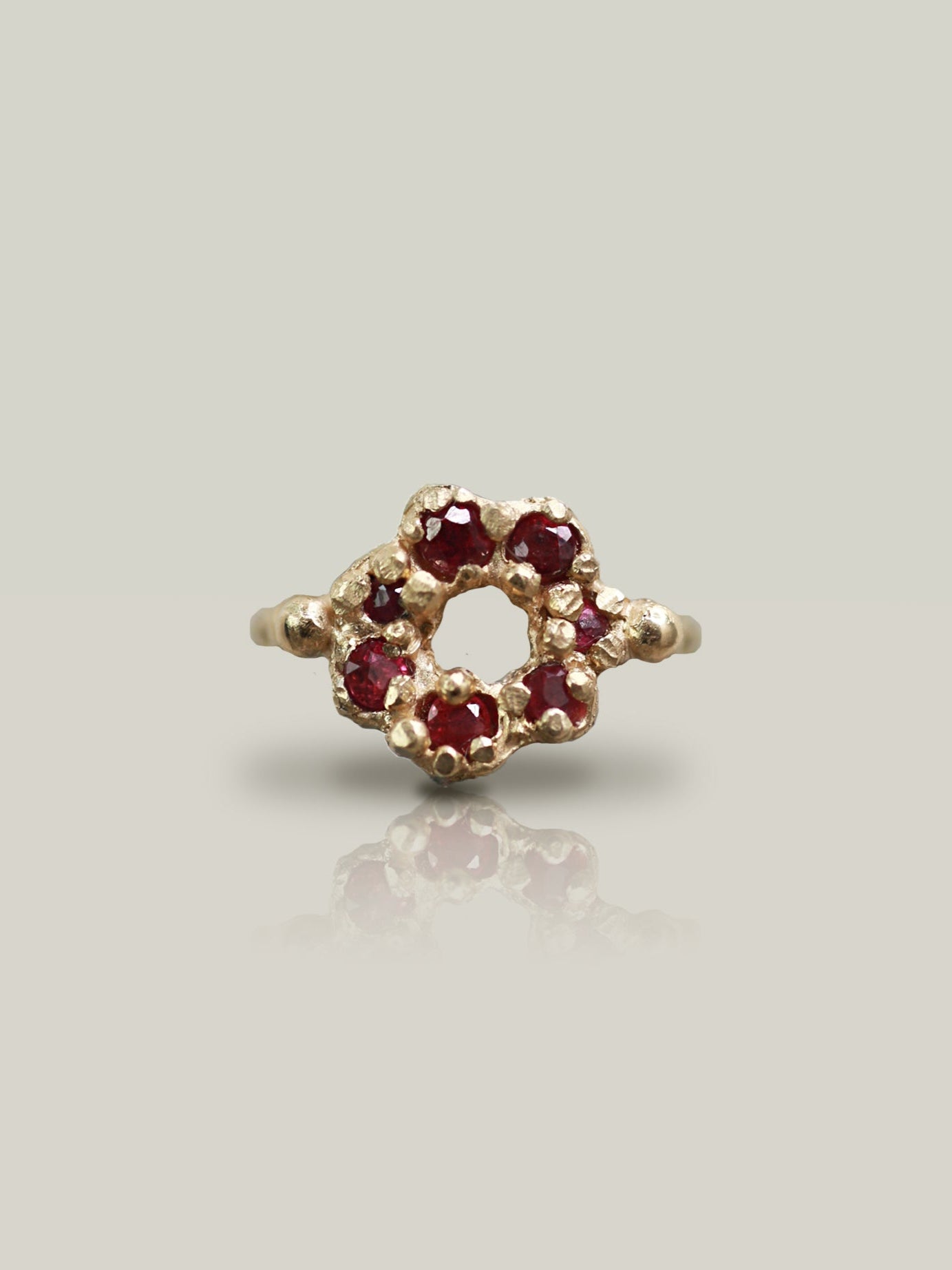 Gold ring with red gemstones on a light gray background