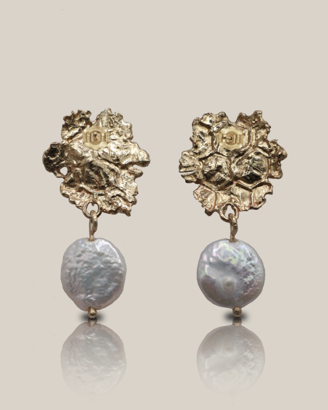 Pair of gold floral earrings with pearl-like beads on a light gray background