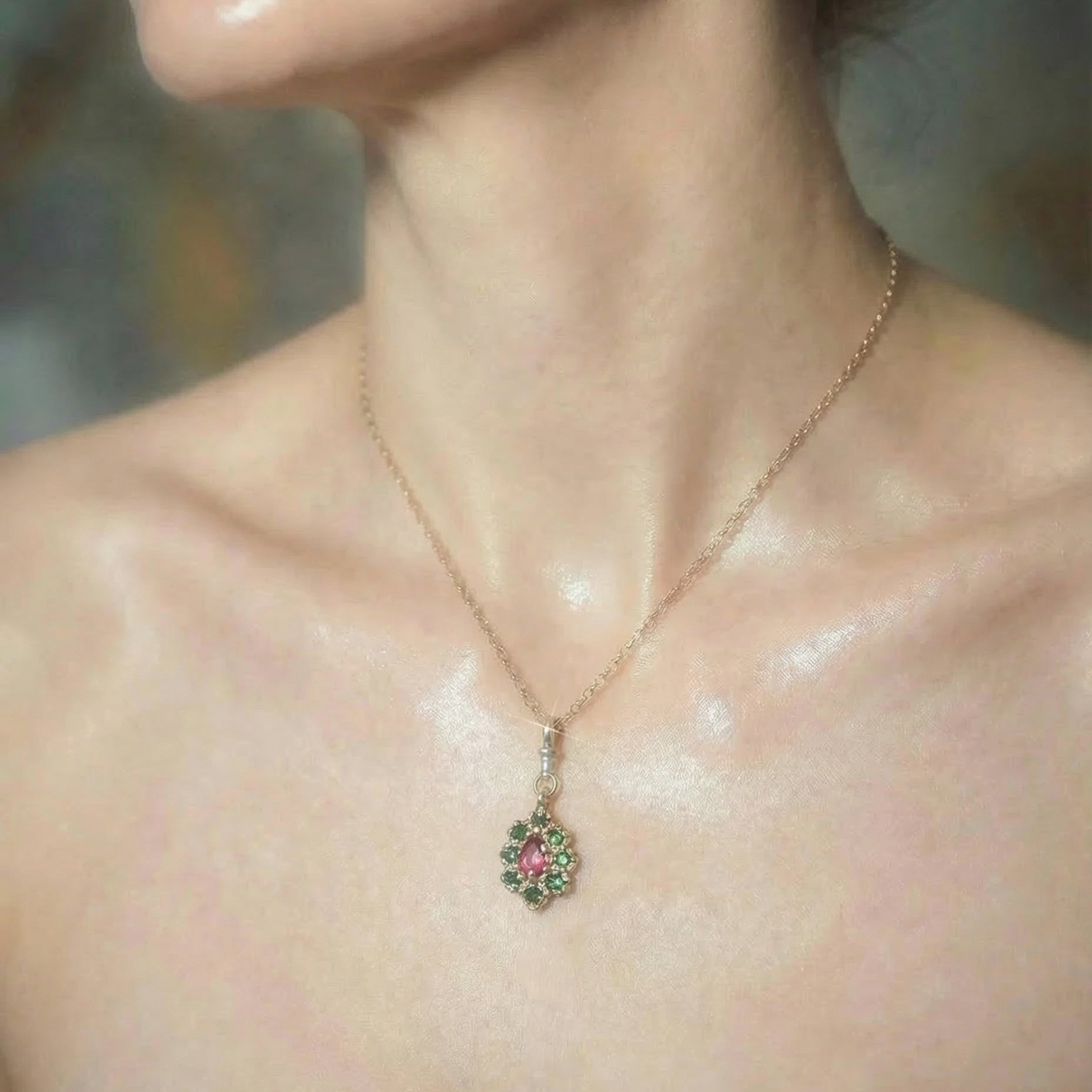 Close-up of a 9ct yellow gold necklace set with a central ruby and surrounding emeralds on a model