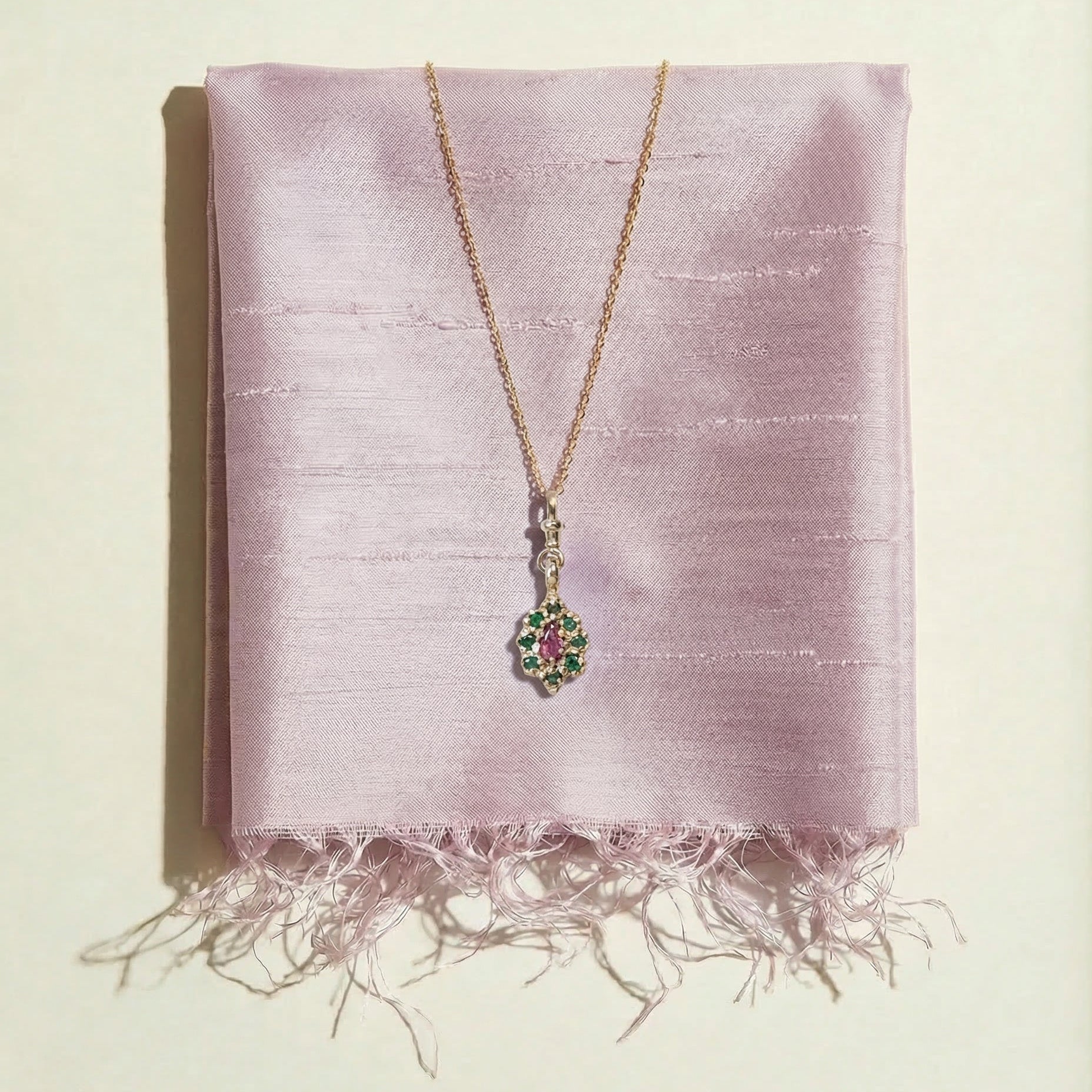 9ct gold victorian inspired Pendant necklace on a pink dupion fabric background set with ruby and emeralds