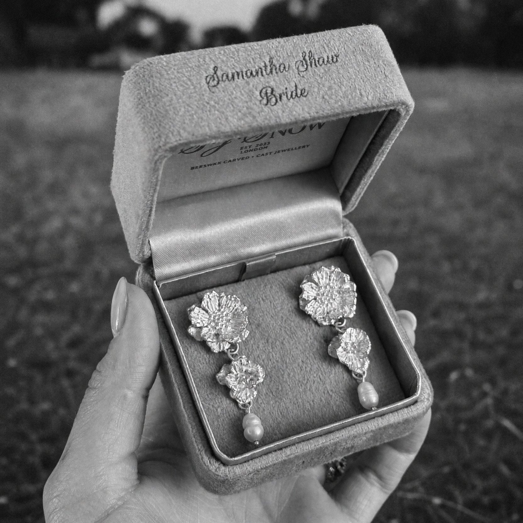 Bridal earrings in a personalized jewelry box against a blurred natural background