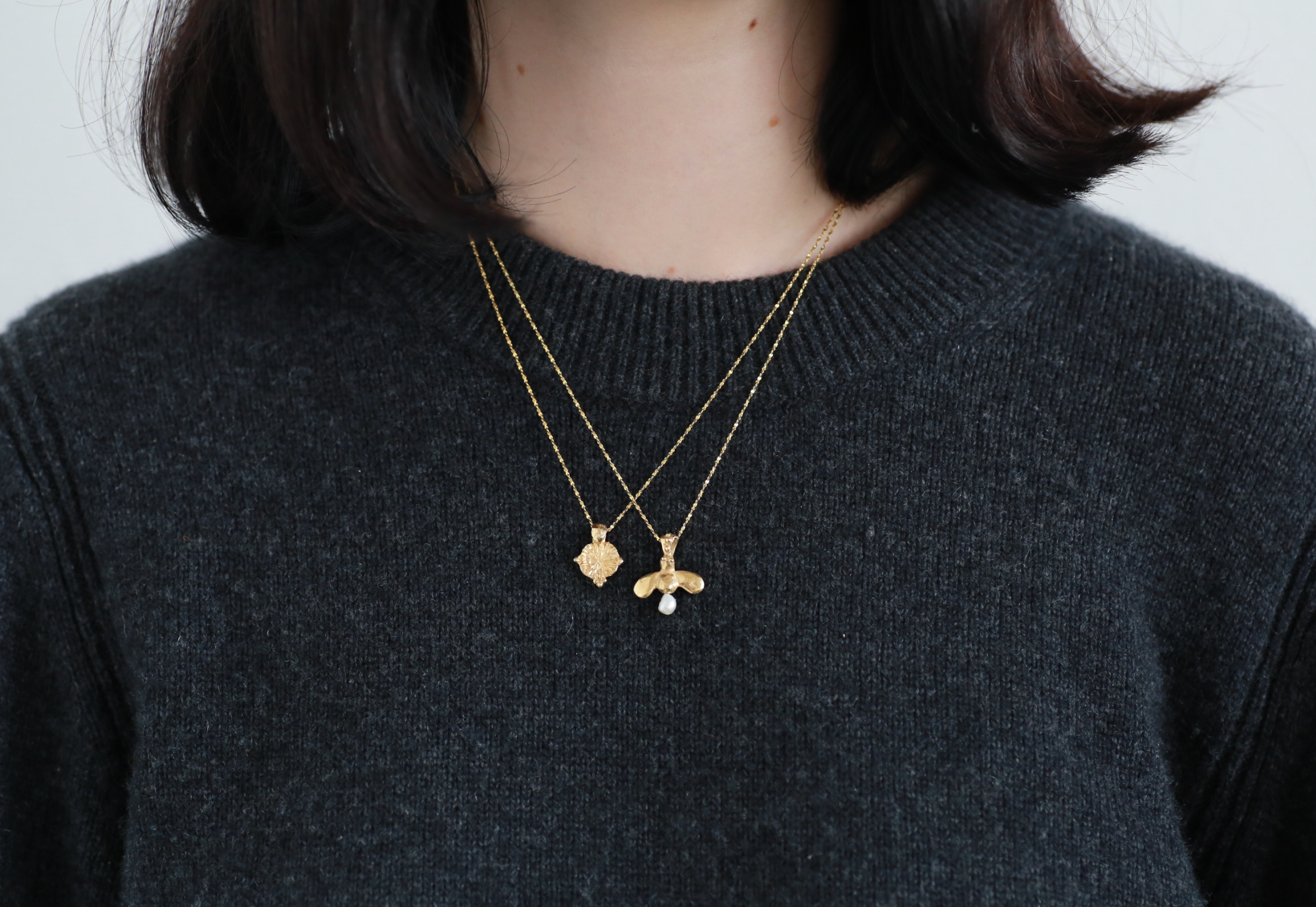 model wears the forget me not amulet and the queen bee necklace in gold vermeil stacking set