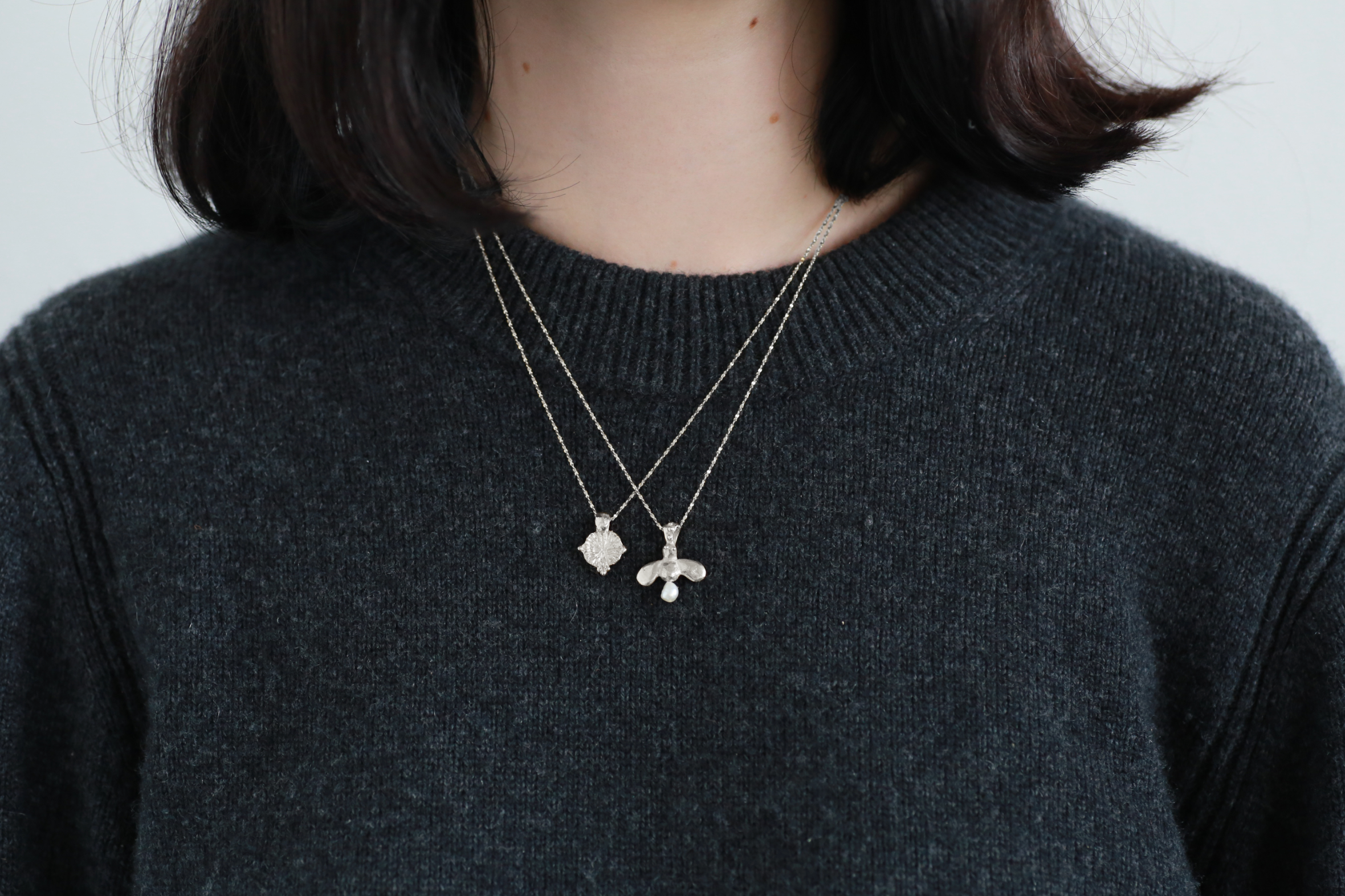 model wearing the forget me not amulet necklace and the queen bee necklace in sterling silver